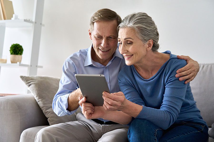 Client Center - Portrait of a Mature Couple Sitting on the Sofa in the Living Room Using a Tablet Together